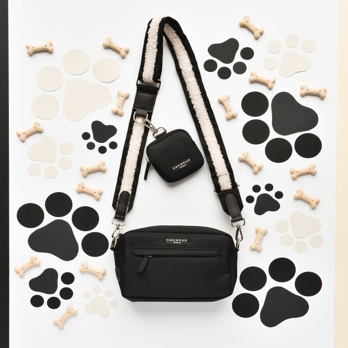 Black Cocopup London dog walking bag bundle with dog biscuits and paw prints on a white background.
