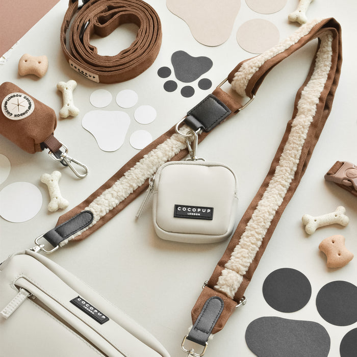 Brown Aviator dog walking bag bundle by Cocopup London, displayed on a paw print patterned surface.