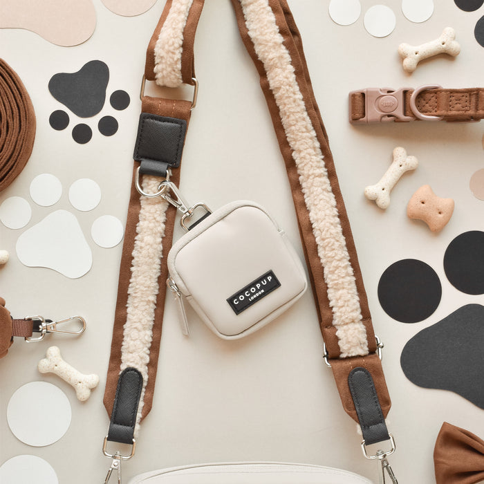 Brown Aviator Cocopup London dog walking bag bundle displayed on a paw print background.