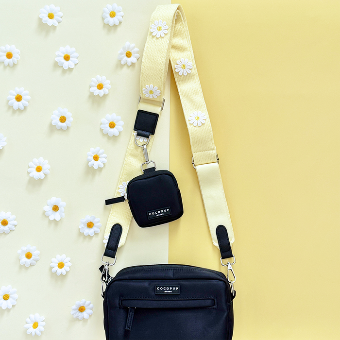 Buttercup yellow Cocopup London dog walking bag and treat pouch on a cream and yellow daisy-patterned background.