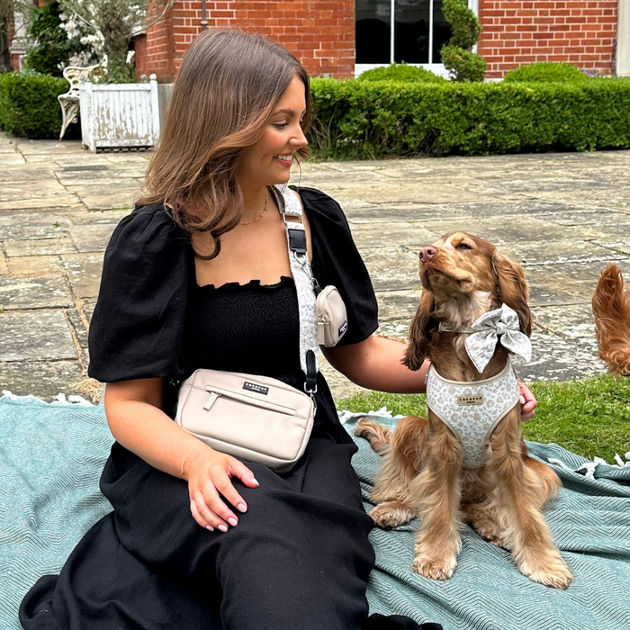Woman with smiling dog in floral bow and harness, next to Cocopup London Luxe Dog Walking Bag Bundle in Garden Meadow print.