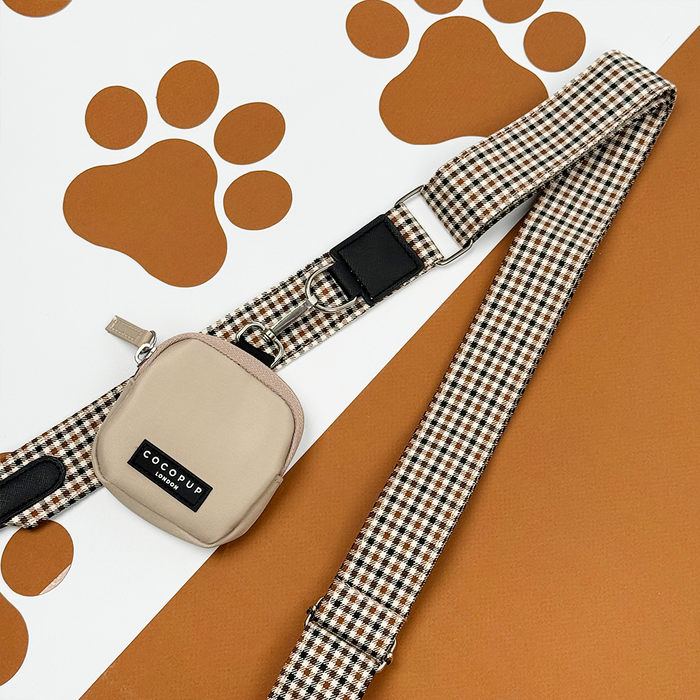 Cocopup London Dog Walking Bag in Heritage Check with beige treat pouch, displayed on brown paw print background.