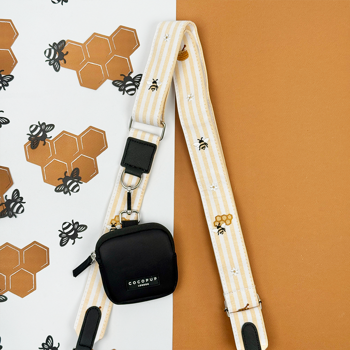 Pale yellow and white striped Bag Strap with bee and honeycomb embroidered decals. Attached is a Cocopup Treat Pouch in black.