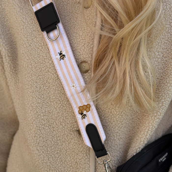 Tan fleece jacket paired with a Cocopup London Honey Meadow bag strap and striped bee-patterned accessory.