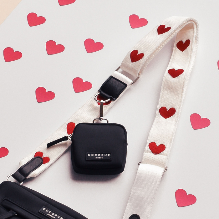 Cocopup London bag strap with red hearts and heart cutouts on a knitted material.