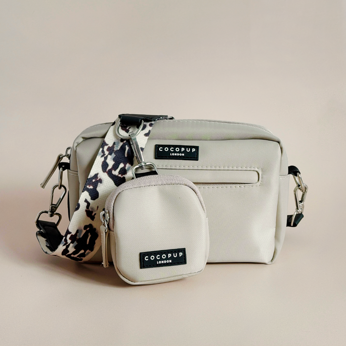 Ivory tortoiseshell Cocopup London dog walking bag with treat pouch and patterned strap on a plain background.