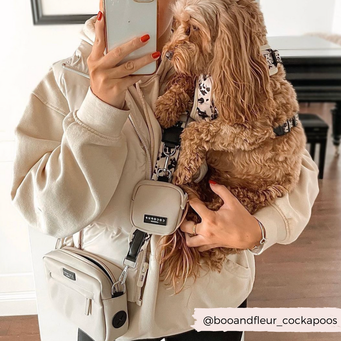 Person in beige hoodie holding a brown dog; both have matching ivory tortoise Cocopup London dog walking bag bundles.