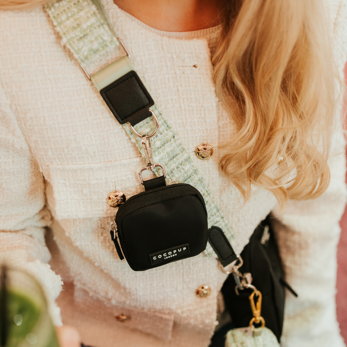 Woman wearing a tweed jacket, carrying a black Cocopup Dog Walking Bag with a green textured Cocopup bag strap.