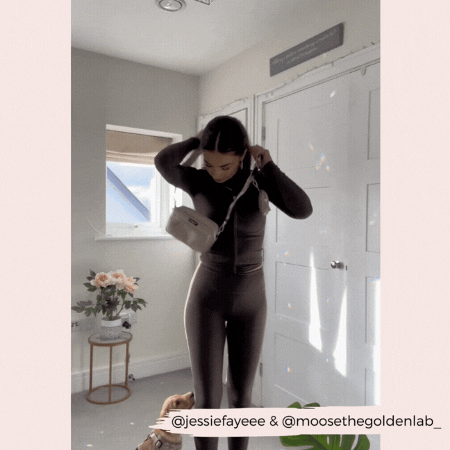 Woman in black with a mocha floral Cocopup London dog walking bag; her dog sits nearby in a well-lit room.