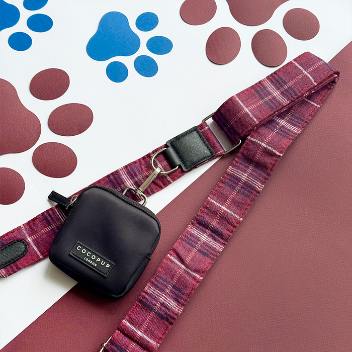 Cocopup London dog walking bag bundle in mulberry plaid on a surface with paw prints.