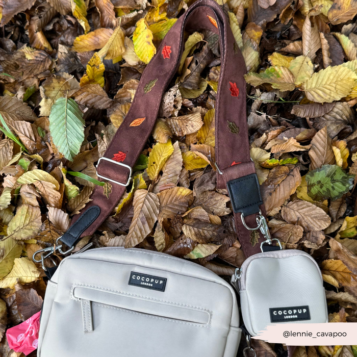 Cream crossbody dog walking bag with brown strap featuring a leaf pattern.