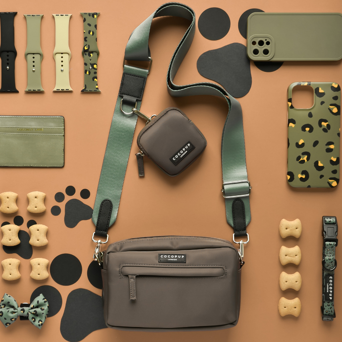 Khaki Cocopup London dog walking bag with treats and accessories, displayed on a paw-print background.