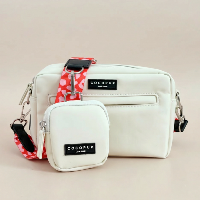 Red and pink leopard print dog walking bag with matching treat pouch and strap on a beige background.