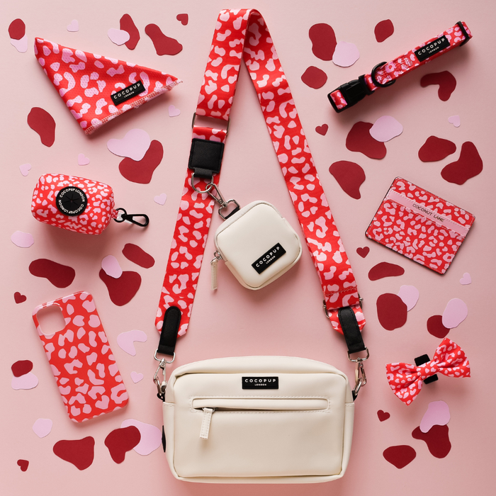 Red and pink leopard print Cocopup dog walking bag with matching accessories on a pink spotty background.