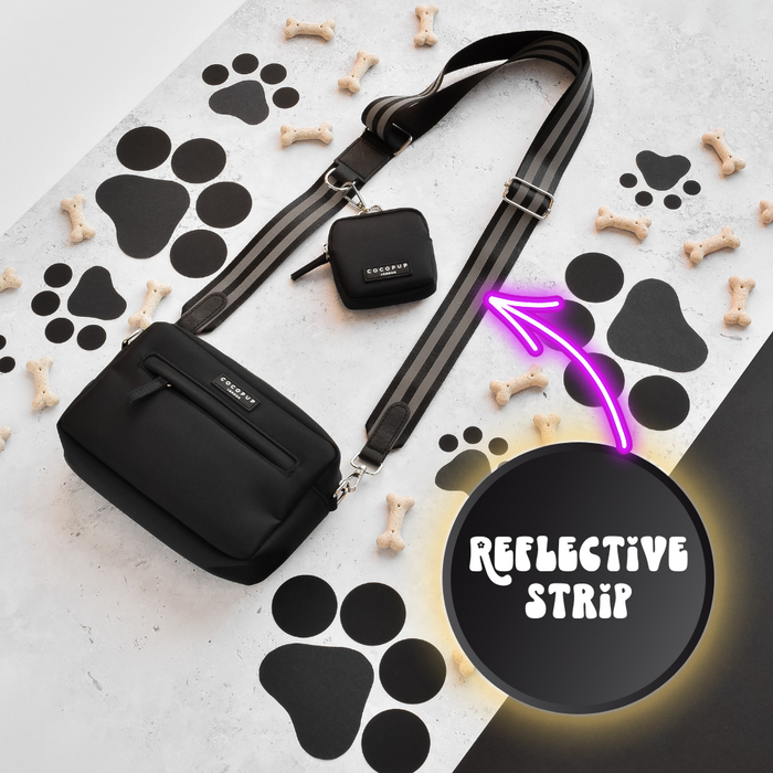 Reflective black dog walking bag with neon arrows strap, set against a paw print and bones patterned background.