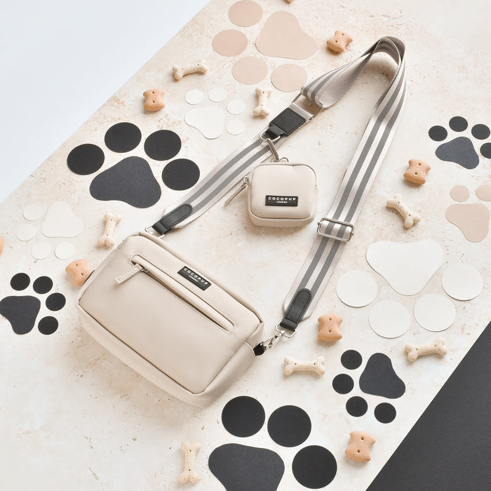 Reflective nude Cocopup London dog walking bag bundle with dog bone treats on a paw print patterned surface.