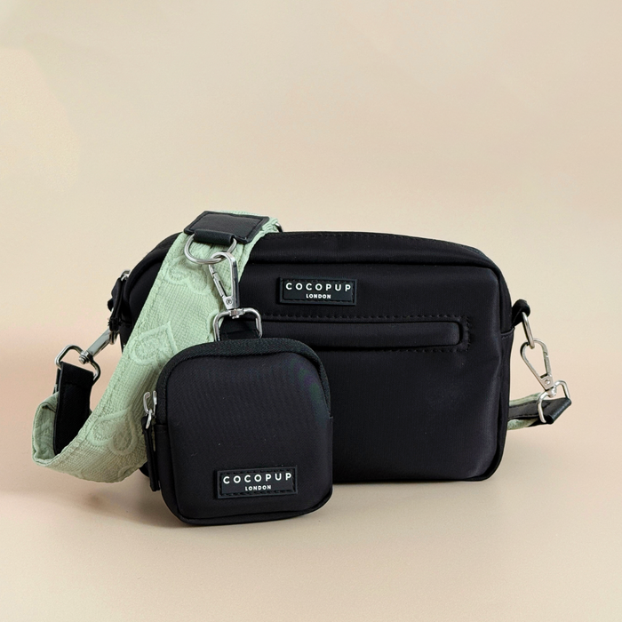 Sage green dog walking bag with heart pattern, matching treat pouch, small pouch, and green strap on beige background.