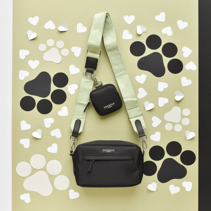 Sage green dog walking bag with heart and black paw print pattern, light background, and green strap.