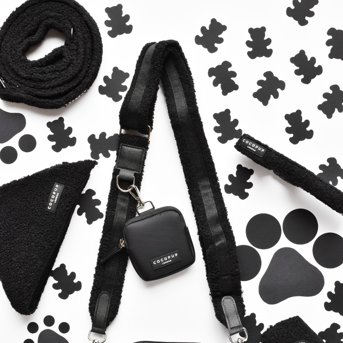 Cream teddy-texture dog walking bag with matching leash, harness, bandana, and treat pouch on a playful background.