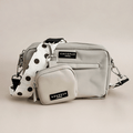 Light gray handbag with matching pouch and polka dot strap on a beige background