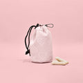 Baby pink heart Cocopup London drawstring treat pouch next to dog treats on a pink background.
