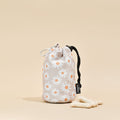 Daisy Chain drawstring treat pouch by Cocopup London with three treats on a beige background.