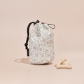 Garden Meadow print treat pouch with black drawstrings next to three bone treats on a beige background.