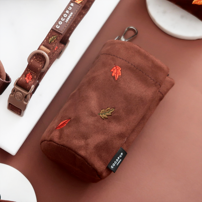 Brown suede treat pouch with embroidered leaf design and a metal clip.