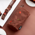 Brown suede treat pouch with embroidered leaf design and a metal clip.