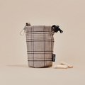 Pup Plaid drawstring treat pouch with metal clip and black tag, displayed with treats on a beige background.