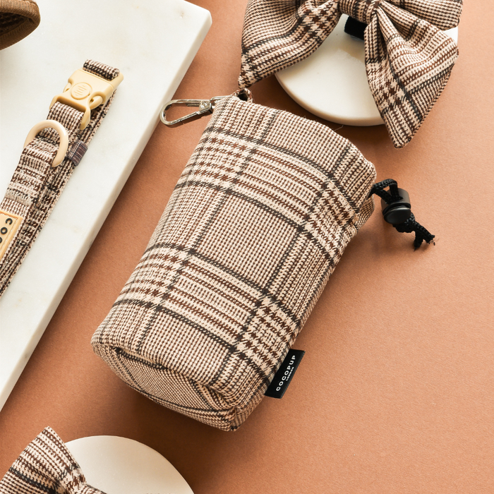 Plaid drawstring treat pouch with matching leash and bow, all in tan tones, shown on a tan surface.