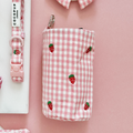 Pink Cocopup London drawstring treat pouch with strawberry print beside a matching pink and strawberry-patterned collar.
