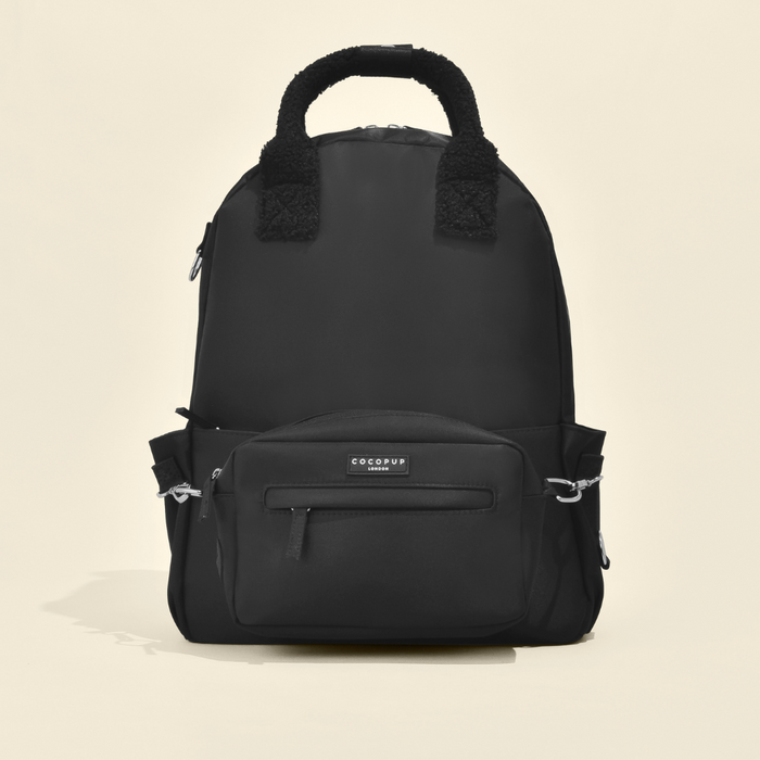 Black Cocopup London rucksack with front and side pockets, fabric handle, shown against a plain light background.