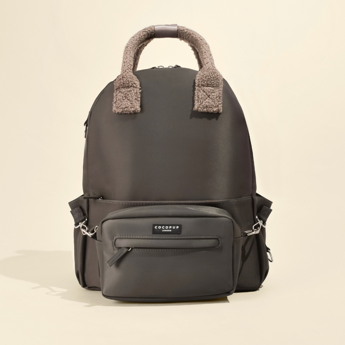Mocha rucksack with front pocket and faux fur handle on a beige background.
