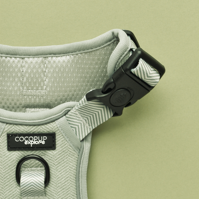 Sage green tweed dog harness with black buckle and Cocopup London label on a matching green background.