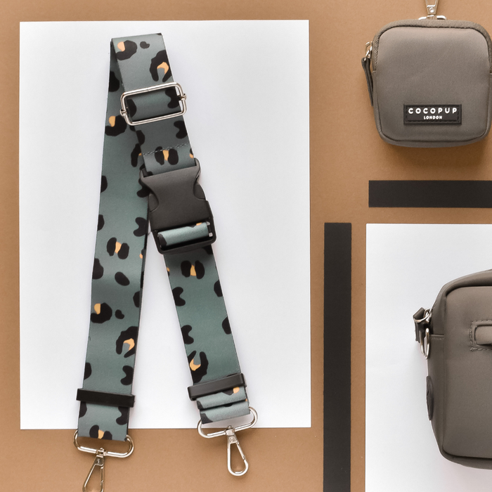 Khaki leopard print Cocopup London bum bag strap shown with two taupe bags on a brown and white geometric background.