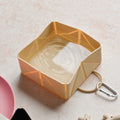 Nude Cocopup London foldable travel bowl filled with water on a light-colored surface.