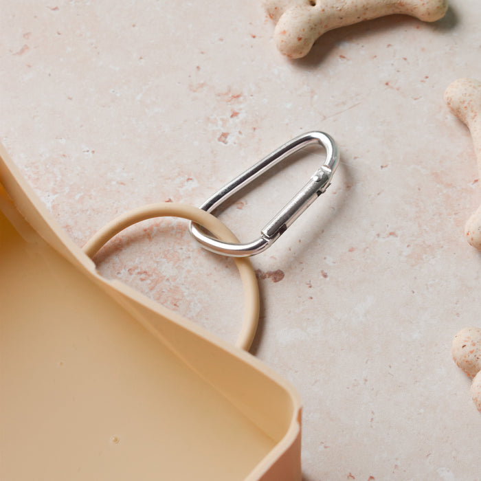 Nude Cocopup London foldable travel bowl with beige strap, metal carabiner, and treats.