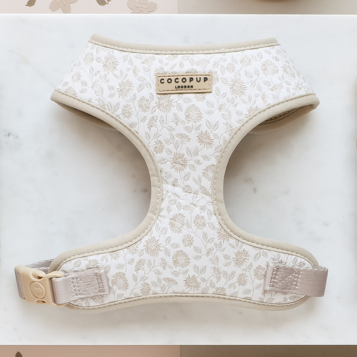 The Luxe Adjustable Neck Harness - Garden Meadow from Cocopup London features a chic embroidered design with a floral pattern and beige trim, laid flat on a white surface. It includes a beige buckle and a gold-tone label that reads "COCOPUP LONDON," making this fashion-forward harness the perfect blend of style and function for your dog.