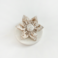 Beige Cocopup collar flower with textured leaf pattern, displayed on a round white surface.