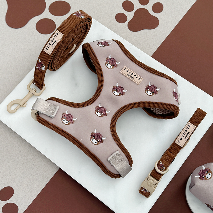 Brown and beige Highland Cow harness, lead, and collar set by Cocopup London on a marble surface.