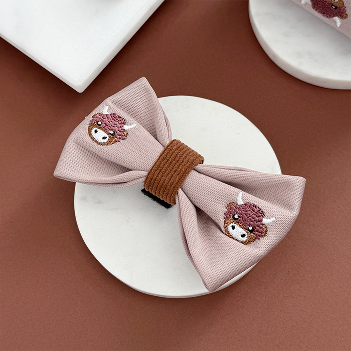 Pink hair bow clip featuring a cartoon cow pattern.
