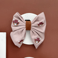 Pink Cocopup London bow clip with embroidered cow faces and a fabric finish.