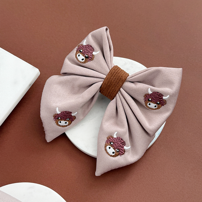 Pink sailor bow tie with brown cartoon cow faces and a solid brown center from Cocopup London.