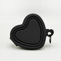 Black collapsible dog bowl with white heart pattern and a metal carabiner attached to the rim.