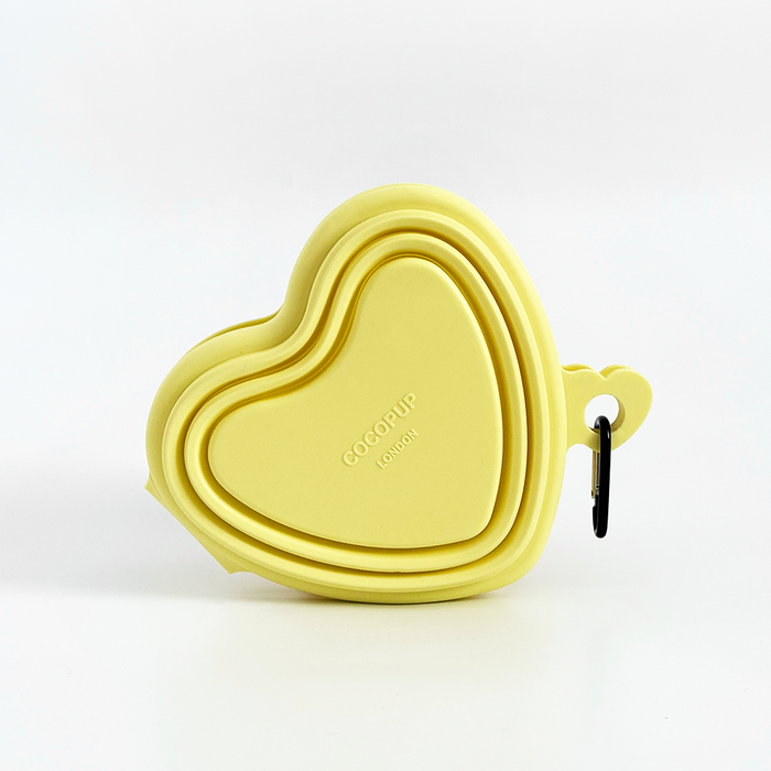 Butter yellow heart-shaped collapsible pet bowl with a carabiner, by Cocopup London.