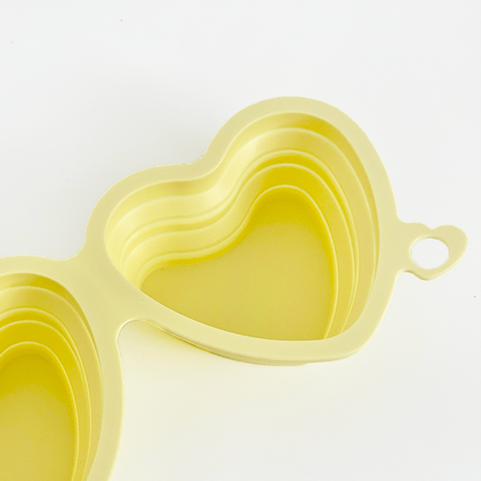 Cocopup London collapsible pet bowl in butter yellow with heart design, made of flexible material.