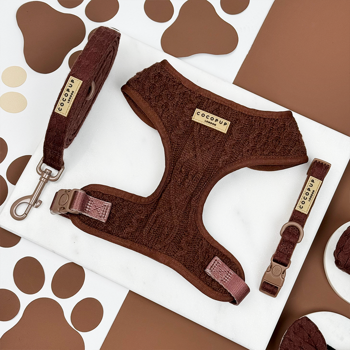 Brown cable knit adjustable harness, lead and collar set by Cocopup London on marble with a paw print background.