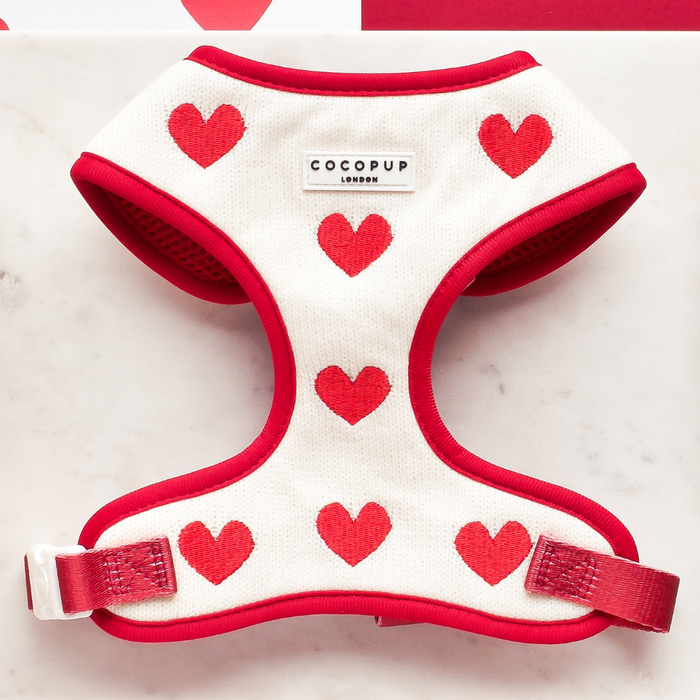 Knitted adjustable neck harness with red trim and heart pattern by Cocopup London, displayed on a marble surface.