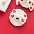White dog bow tie with red hearts, knit texture, displayed on a red background.